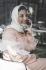 Femme marocaine avec hijab et robe arabe traditionnelle parlant au téléphone derrière le panneau de fenêtre — Photo de stock