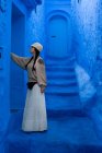 Женщина трогает синюю окрашенную стену на улице в Марокко — стоковое фото