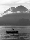 Uomo che naviga sul lago con le montagne — Foto stock