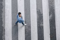 Jovem adolescente elegante olhando para cima e cruzando estrada na zebra — Fotografia de Stock