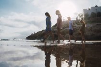 Donna e adolescenti che camminano insieme sulla spiaggia — Foto stock