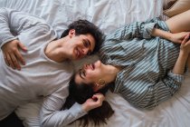 Allegro giovane uomo e donna sdraiati sul letto — Foto stock