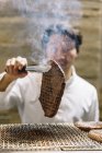 Chef preparando carne asada en restaurante - foto de stock