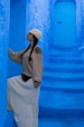 Женщина трогает синюю окрашенную стену на улице в Марокко — стоковое фото