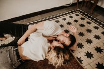 Happy romantic man and woman lying on floor and kissing at home — Stock Photo