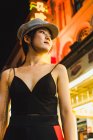 Молоді азіатські жінки стоять на освітленій вулиці вночі і дивитися вбік — стокове фото