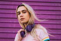 Portrait de jeune femme blonde avec casque violet contre le mur violet — Photo de stock