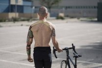Shirtless handicapped sportsman walking with bicycle — Stock Photo