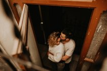 Весёлый мужчина и женщина стоят и обнимаются у окна дома — стоковое фото