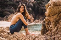 Портрет привабливої топлес жінки, що сидить на скелі в озері — стокове фото