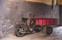 Старый мотоцикл перед потрепанной серой стеной на улице — стоковое фото