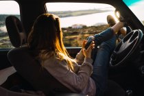 Frau benutzt Smartphone im Auto an der Küste — Stockfoto