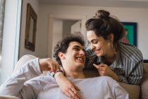 Fröhliches junges Paar lacht auf Couch — Stockfoto
