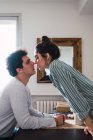 Afetuoso jovem casal beijando à mesa — Fotografia de Stock