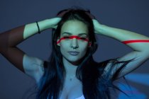 Jovem mulher atraente com linha vermelha no rosto e braço no fundo escuro — Fotografia de Stock