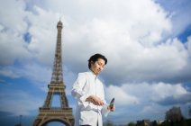 Японский шеф-повар с ножами стоит перед Эйфелевой башней в Париже — стоковое фото