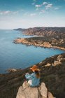 Femme sur le rocher à l'océan et regardant loin — Photo de stock