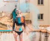Magra donna sessuale in lingerie nera ricoperta di colorate polveri secche in piedi sul balcone — Foto stock