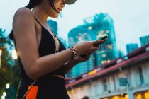 Mulher asiática em roupas elegantes usando smartphone na rua na cidade — Fotografia de Stock
