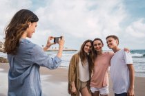 Woman photographing kids with smartphone on beach — Stock Photo