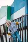 Красива жінка спирається на паркан проти сучасних барвистих будинків — стокове фото