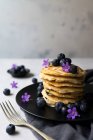 Empilement de délicieuses miettes appétissantes aux myrtilles et fleurs violettes sur plaque noire — Photo de stock