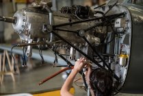 Crop hands of aircraft mechanic fixing engine of small airplane in hangar RELEASE — Stock Photo
