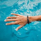Crop main de personne dans l'océan turquoise gestuelle shaka à la côte. — Photo de stock