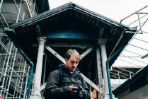 Homme debout et utilisant la caméra devant le vieux bâtiment minable — Photo de stock