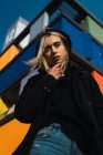 Attraktive blonde Frau blickt in Kamera gegen buntes Gebäude — Stockfoto
