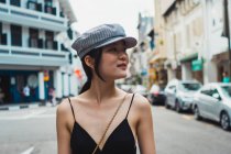 Joven mujer asiática caminando en la calle en la ciudad y mirando hacia otro lado - foto de stock