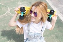 Blonde girl with penny board sitting in skate park — Stock Photo