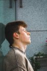 Junger Mann mit geschlossenen Augen und Sommersprossen lehnt am Fenster — Stockfoto