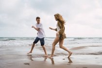 Laughing teenage friends fooling around on seashore in summer — Stock Photo