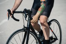 Crop man with artificial arm riding bicycle on asphalt road during race — Stock Photo