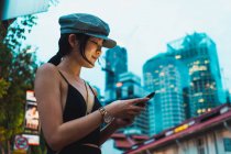 Asiatico donna in elegante vestiti utilizzando smartphone su strada in città — Foto stock