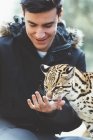 Lächelnder junger Mann füttert Leoparden im Zoo — Stockfoto