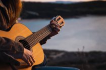 Крупным планом Женщина сидит и играет на гитаре в природе — стоковое фото