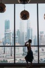 Frau steht am Fenster in Wohnung und blickt auf Hochhäuser — Stockfoto
