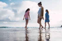 Женщина и девочки-подростки, идущие вместе по пляжу — стоковое фото