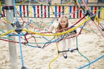 Porträt eines fröhlichen Mädchens, das auf einem Spielplatz an Seilen klettert — Stockfoto