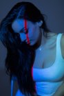 Giovane donna attraente con linea rossa sul viso e sul corpo guardando verso il basso su sfondo scuro — Foto stock