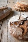 Круглая буханка ржаного хлеба на деревянном столе с мукой — стоковое фото