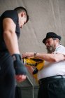 Entrenador adulto atando guante de boxeador en la mano del deportista en el ring. - foto de stock