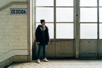 Дорослий чоловік стоїть біля вікна біля сходів у коридорі — стокове фото