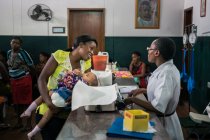 ANGOLA - ÁFRICA - 5 DE ABRIL DE 2018 - Mulher negra sorridente interagindo com a enfermeira na recepção no hospital — Fotografia de Stock