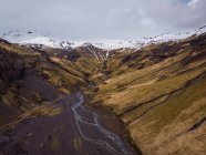 Montañas rocosas nevadas y valle con río, Islandia - foto de stock