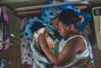 Камерун - Африка - 5 квітня 2018: етнічні жінка і маленька дитина, лежачи на ліжку в лікарні — стокове фото