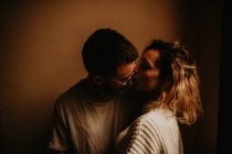 Ласковая молодая пара целуется у стены — стоковое фото