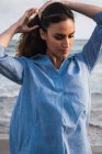Elegante hispanische Frau, die am Strand Haare berührt — Stockfoto